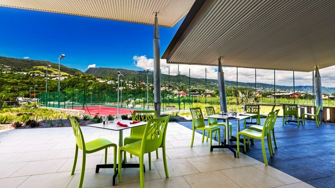 La terrasse du restaurant du Beauséjour Sport Club, surplombant le court de tennis, avec les hauteurs de Sainte-Marie en arrière-plan